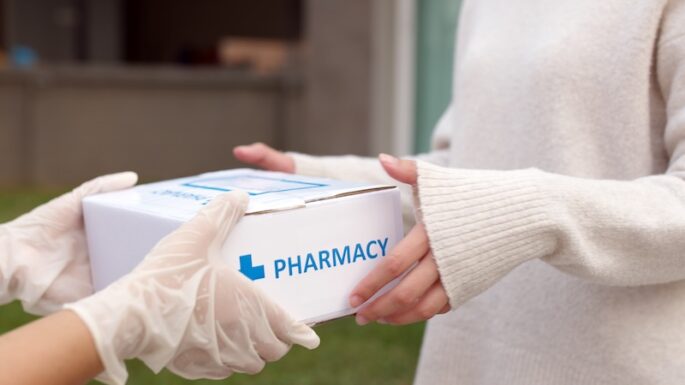 Asian female patient receive medication package box free first aid from pharmacy hospital delivery service at home wear glove in telehealth, telemedicine healthcare insurance online concept.