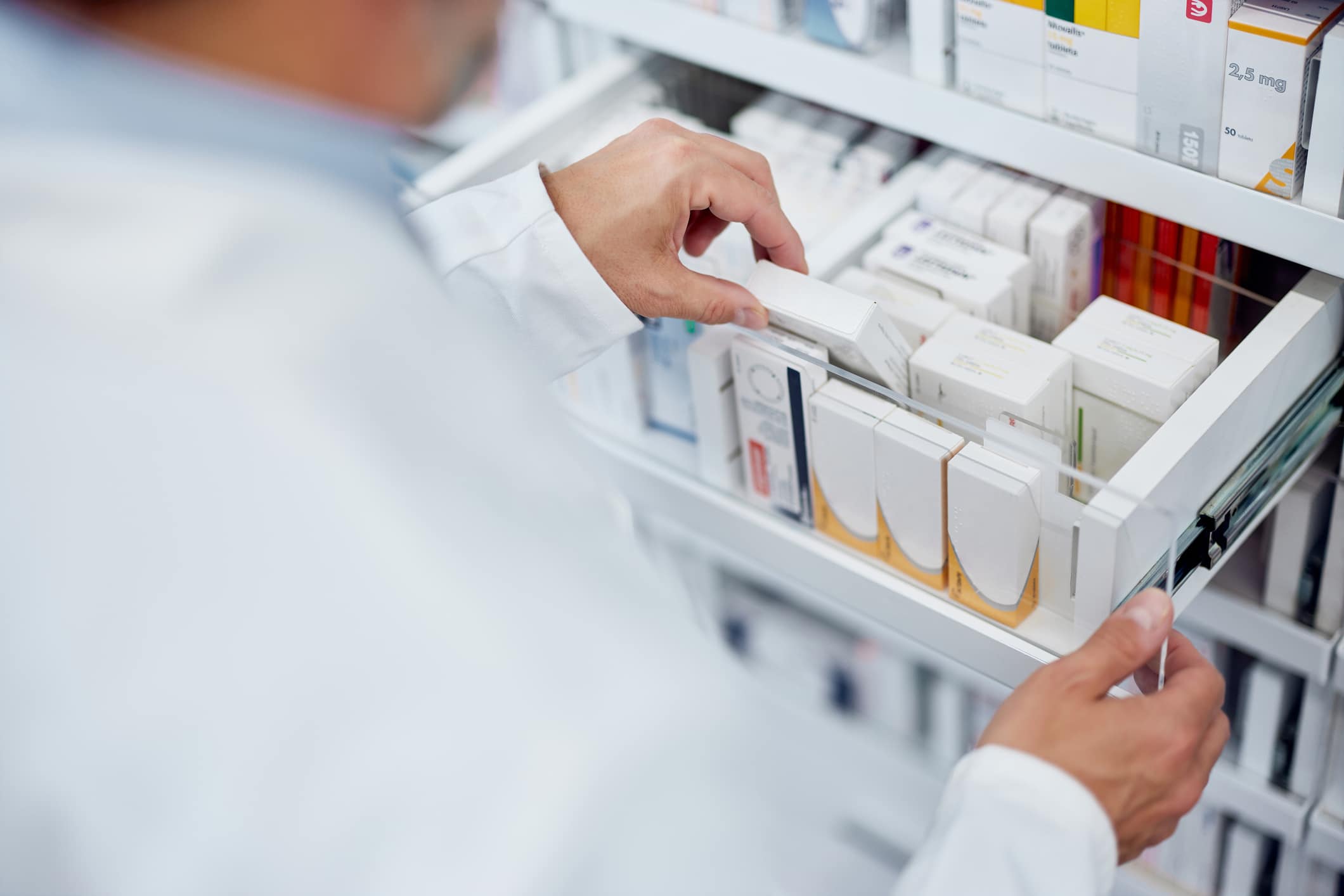 Male pharmacist taking one box of medicine from the drawer.