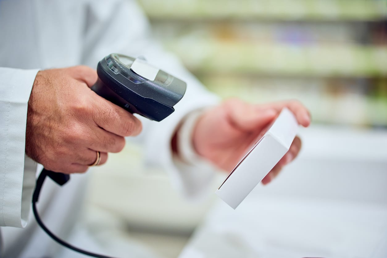 Healthcare professional scanning a medication package with a barcode scanner for medication verification.